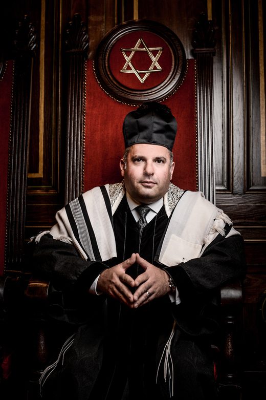 Gideon Zelermyer in canonical robes, tallit and cantor&rsquo;s hat, seated in the cantor&rsquo;s chair.