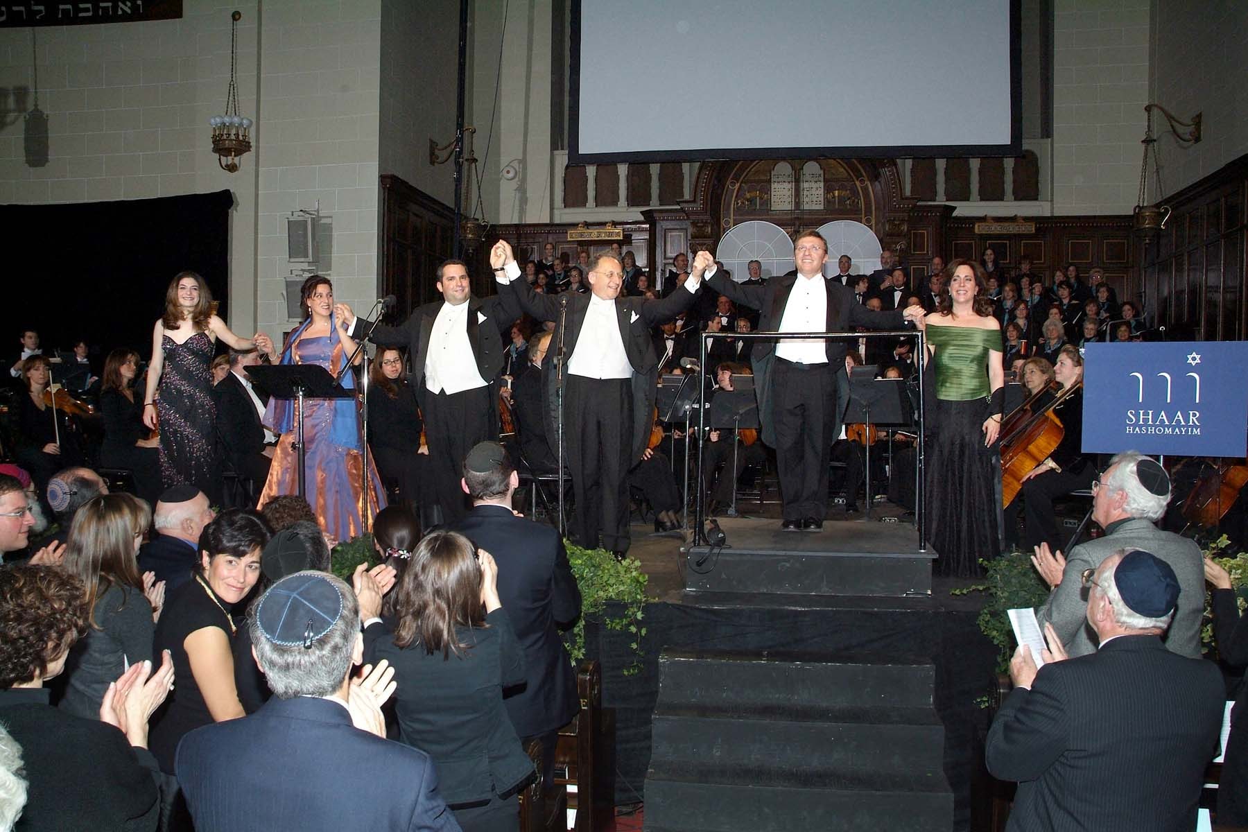 Lindsay Deutsch, Monique Pag&eacute;, Gideon Zelermyer, Boris Brott and Stephen Glass lined up on the platform for the curtain call, the audience on its feet applauding in the foreground.