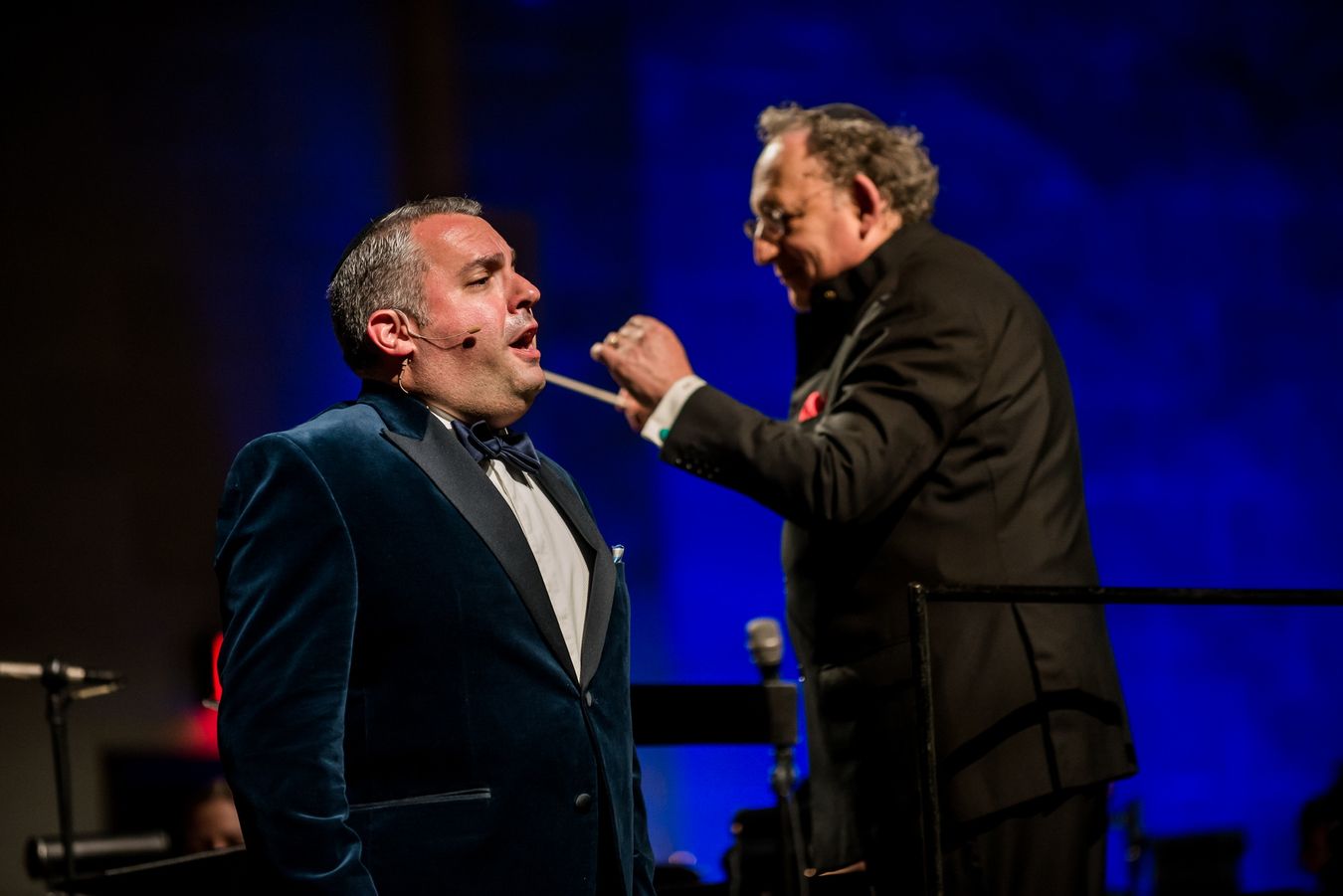 Zelermyer singing in a velvet dinner jacket, with Boris Brott conducting beside him, baton raised.