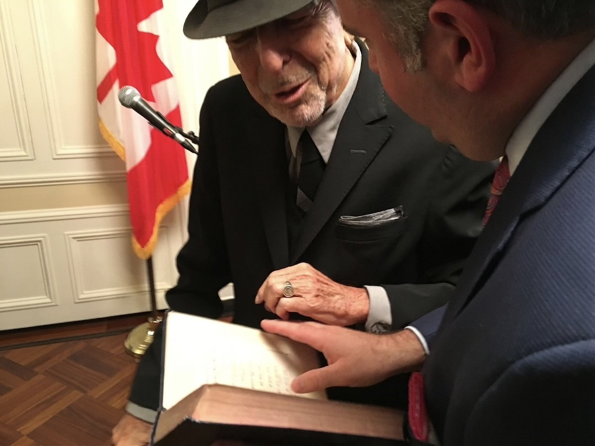 Leonard Cohen leaning in to look at a large open book held by Gideon Zelermyer.