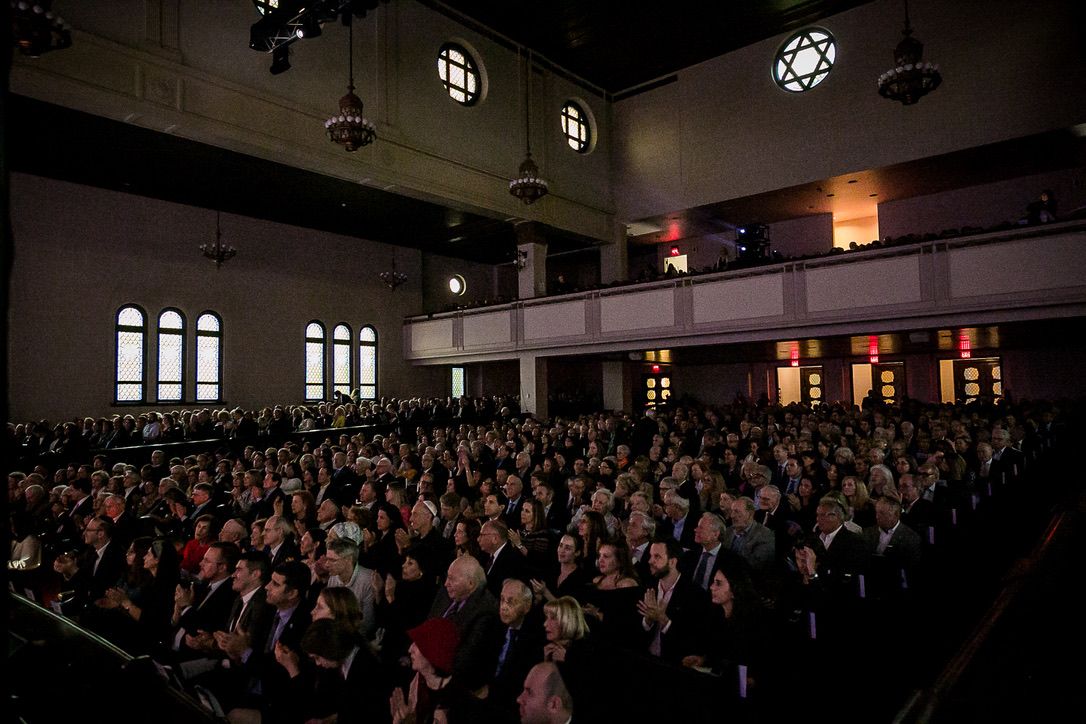 The sanctuary from the stage, full to the balcony, the Star of David windows lit above.