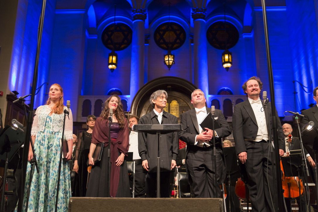 The soloists and conductor taking a bow beneath the sanctuary's three rose windows.