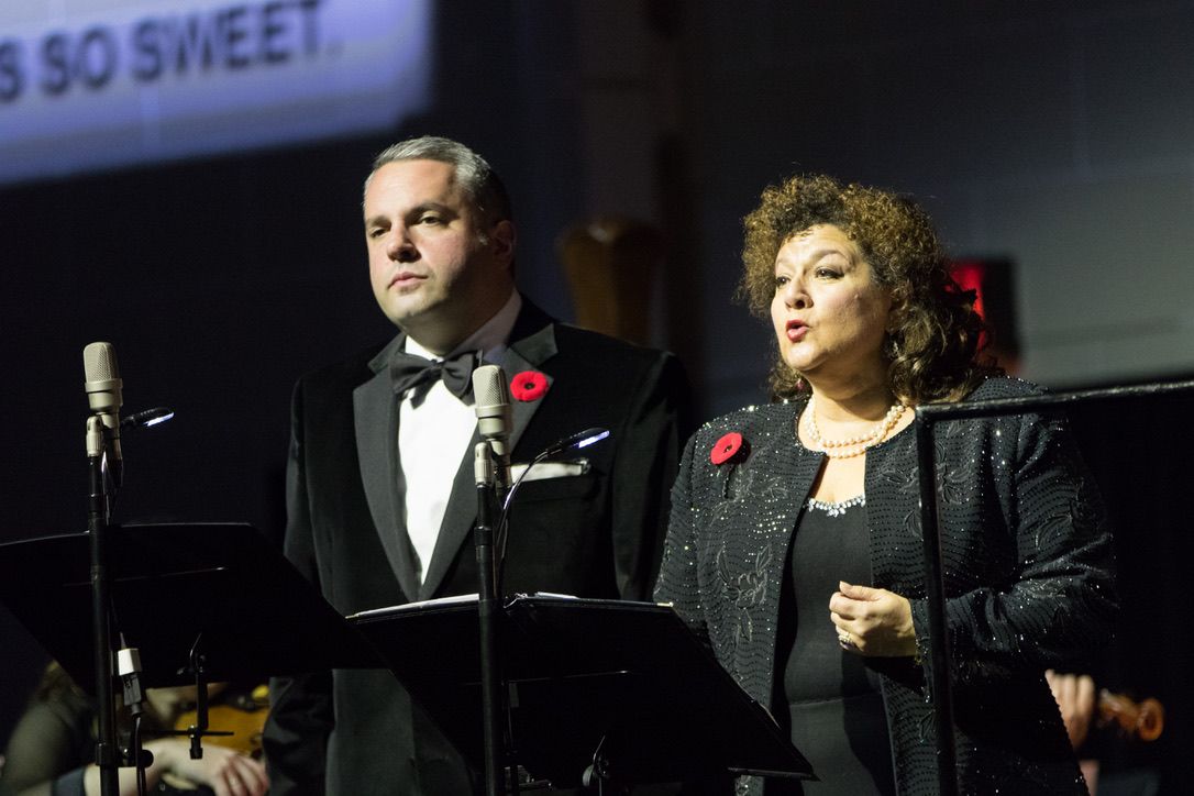 Zelermyer and a soprano singing at adjacent microphones, a projected caption behind them.